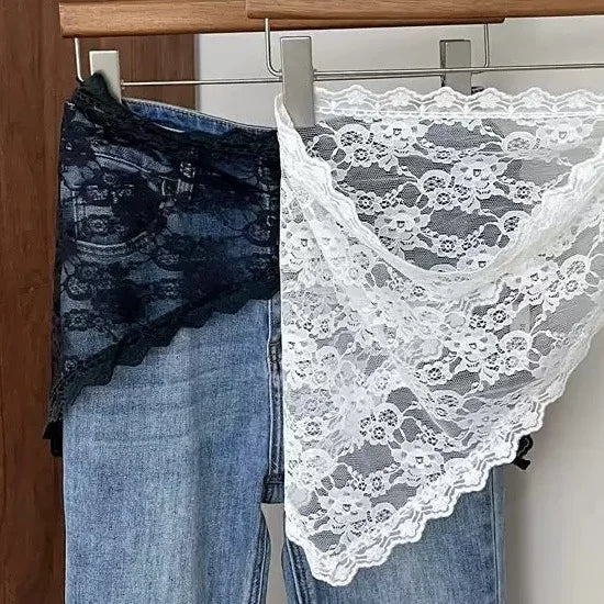 Pair of blue jeans with lace trim hanging on a rack.