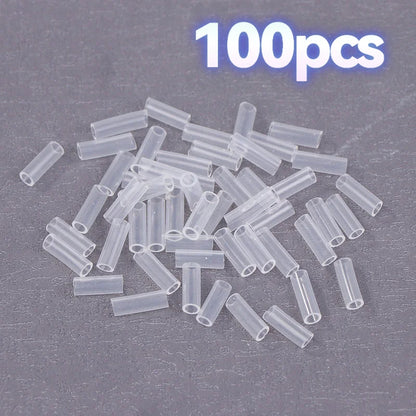A pile of 100 small clear plastic tube connectors on a dark gray textured background, with '100pcs' text in the top right corner.