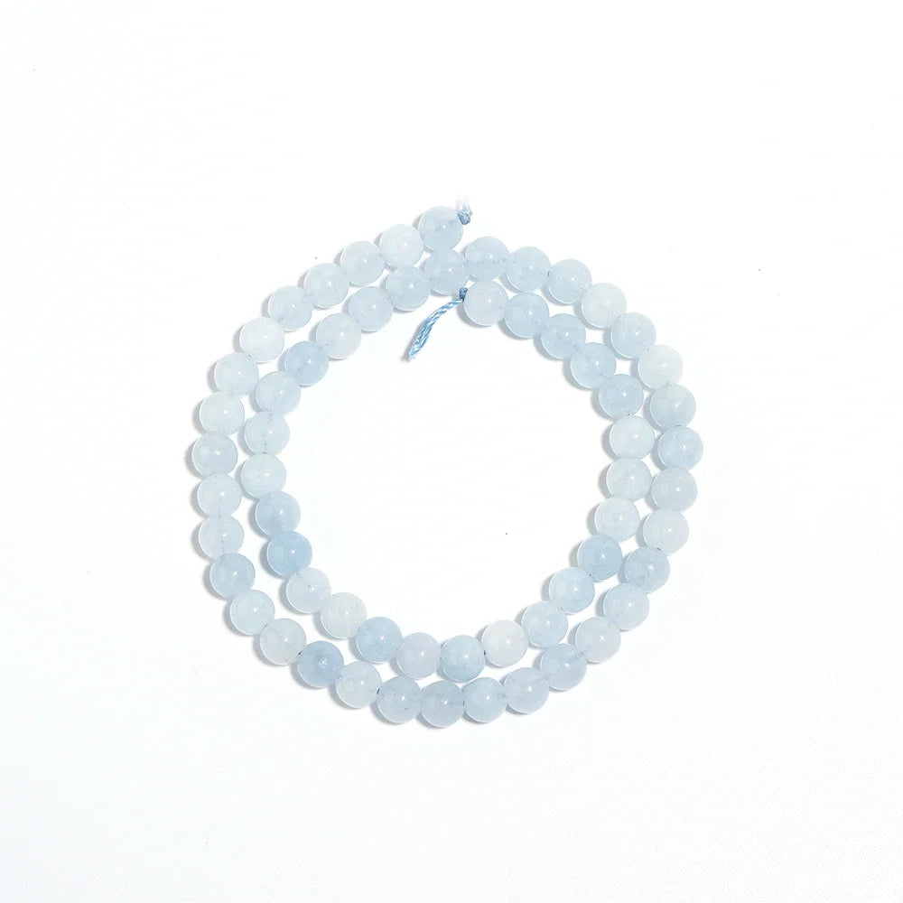 A double-strand beaded necklace made of light blue, semi-translucent round beads, coiled on a plain white background.