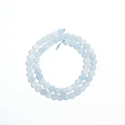 A double-strand beaded necklace made of light blue, semi-translucent round beads, coiled on a plain white background.