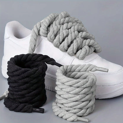White sneakers with black and gray ropes on a light gray background