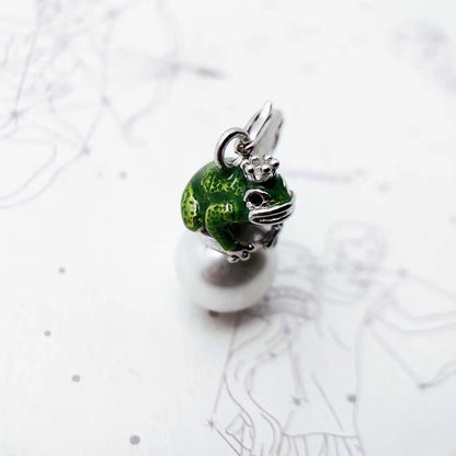 Green and silver frog charm on a white background