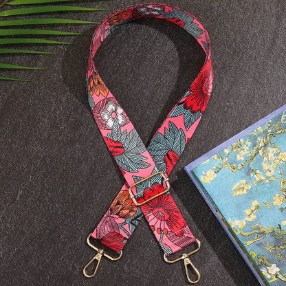Floral patterned strap with gold hardware on a dark surface next to a colorful notebook.