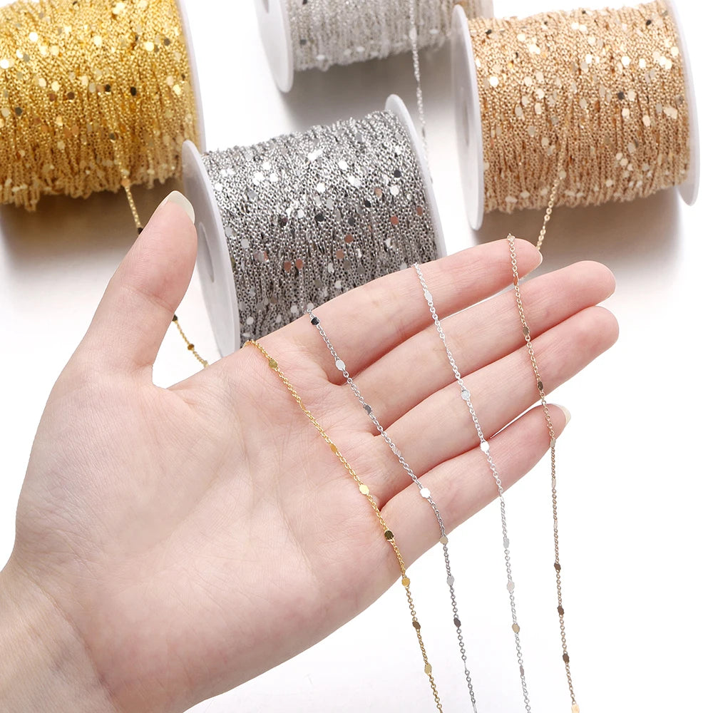 Gold and silver chain spools with a hand holding a chain necklace on a white background