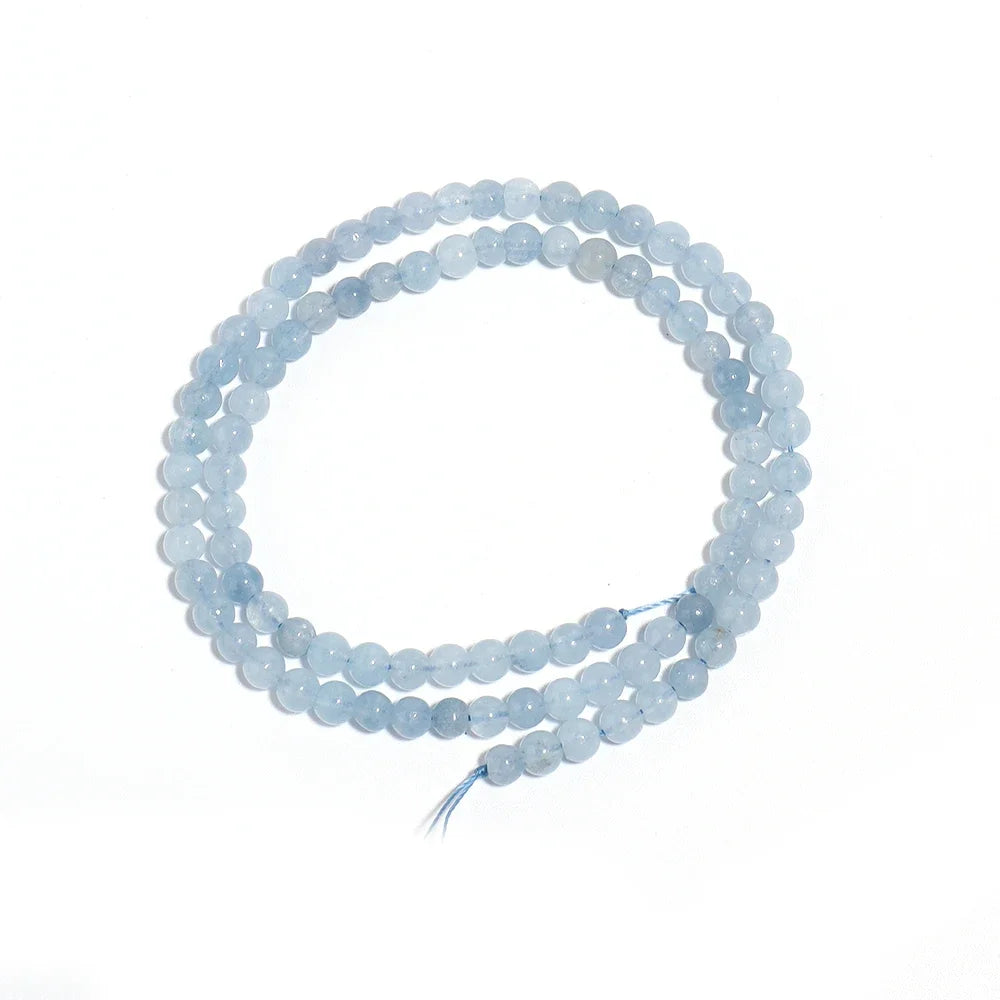 A double-strand beaded necklace made of light blue, semi-translucent round gemstone beads, coiled on a plain white background.