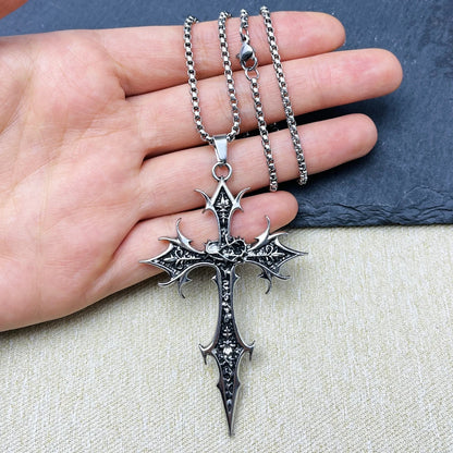 Silver cross pendant necklace on a hand with a neutral background