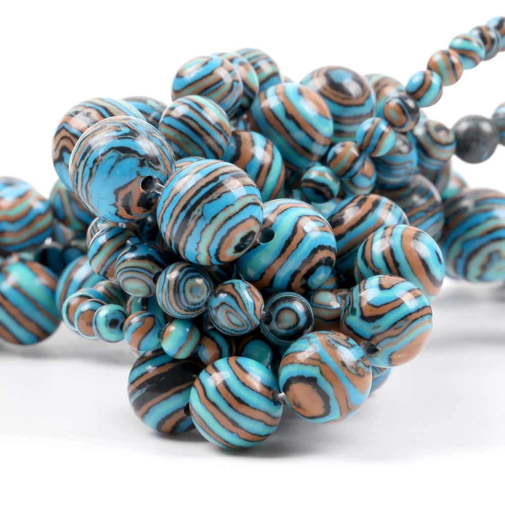 A close-up of a beaded strand featuring large, round marbled beads with swirls of turquoise blue, brown, and black, alongside smaller matching beads and a few dark gray beads, set against a plain white background.