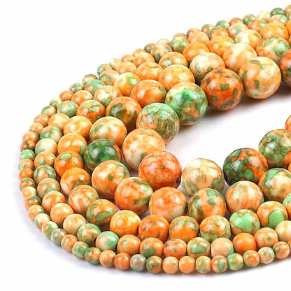 Marbled round gemstone beads in orange, green, and cream, arranged in two strands on a white background.