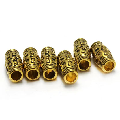 Five gold-colored metal spacer beads with intricate scrollwork patterns, arranged on a plain white background.