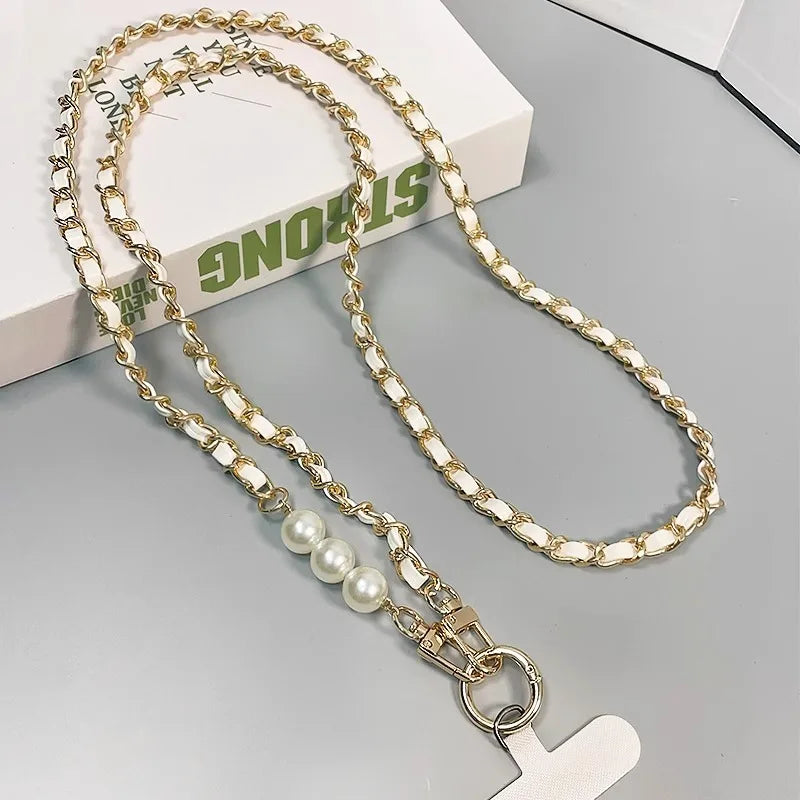 Gold chain lanyard with pearls and a cross charm on a gray surface.