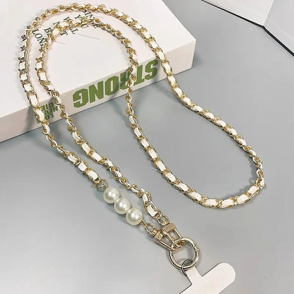 Gold chain lanyard with pearls and a cross charm on a gray surface.