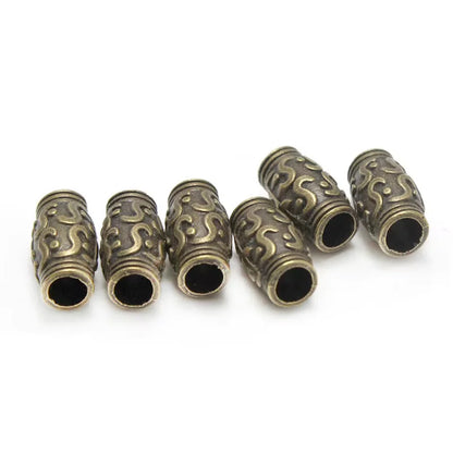 Five antique bronze cylindrical spacer beads with embossed wave patterns, arranged on a plain white background.