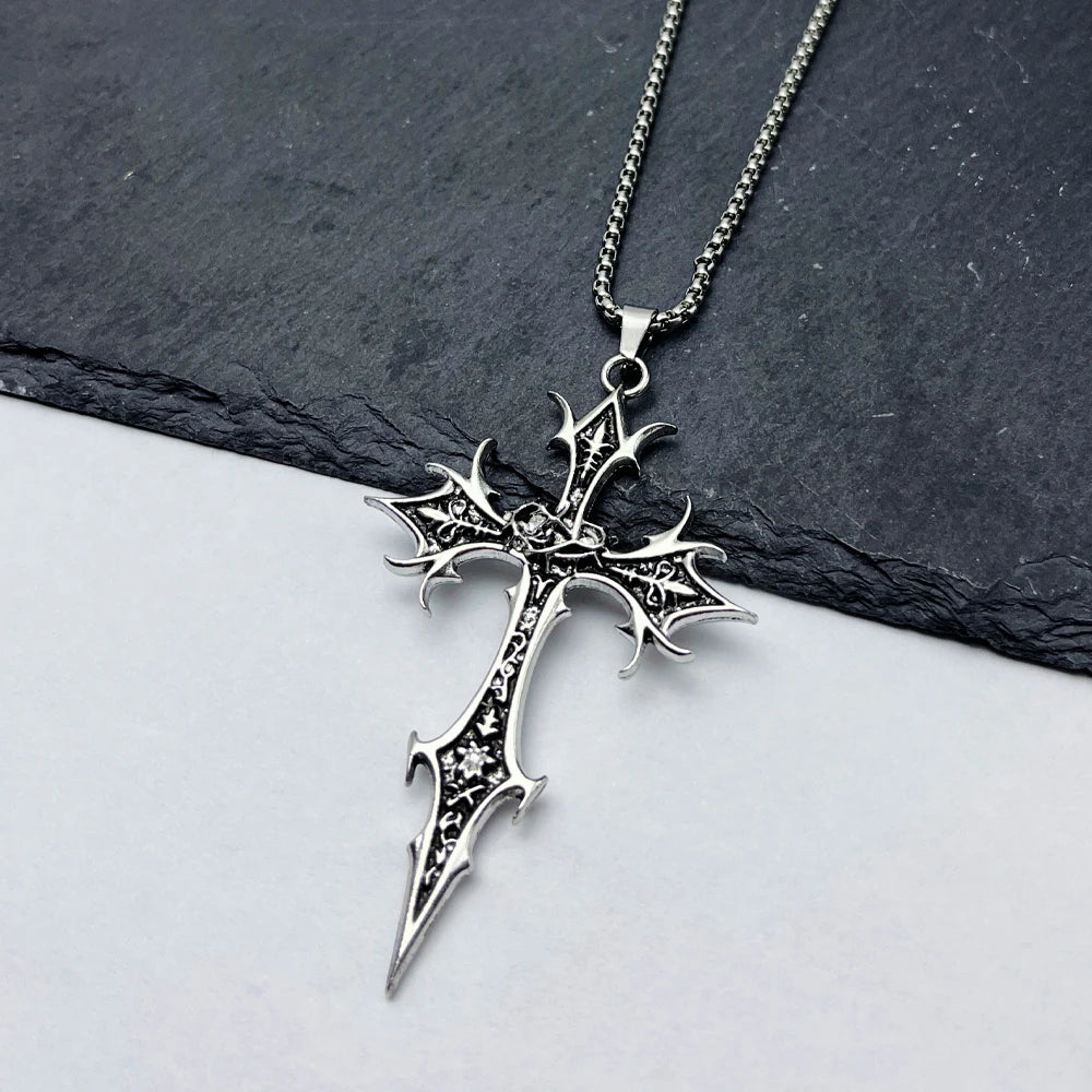 Silver cross pendant necklace on a dark slate surface