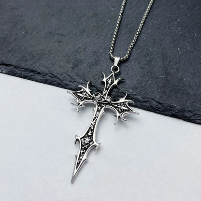 Silver cross pendant necklace on a dark slate surface