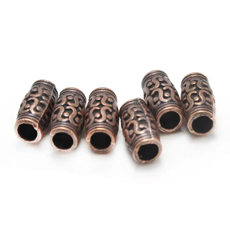 Six ornate cylindrical metal beads with a textured, engraved pattern in a bronze finish, arranged on a plain white background.