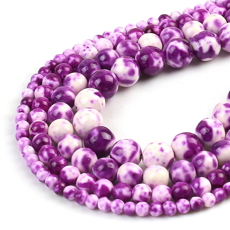 Purple and white marbled round beads strung on a clear cord, photographed on a white background.