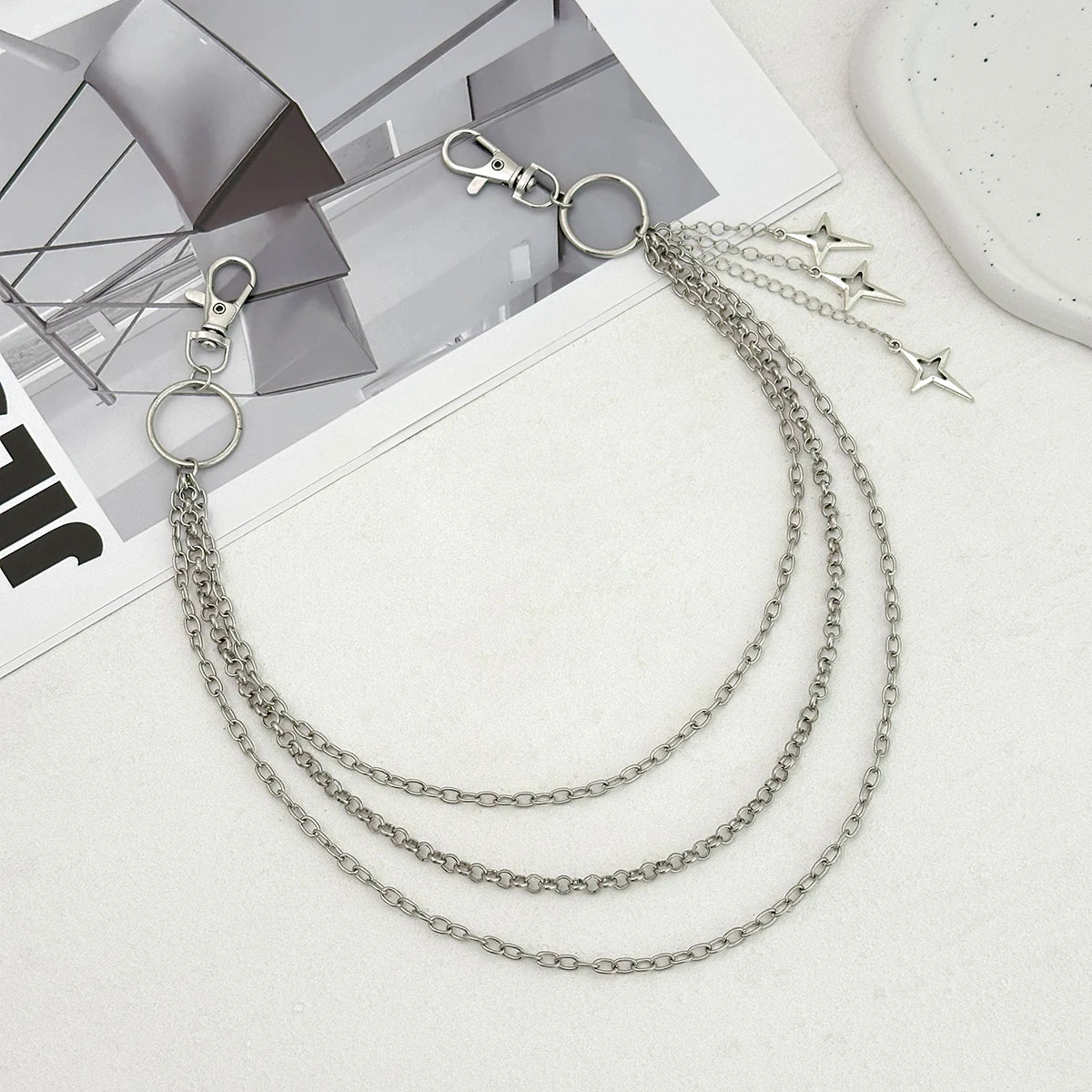 Silver chain necklace with star pendants on a magazine background