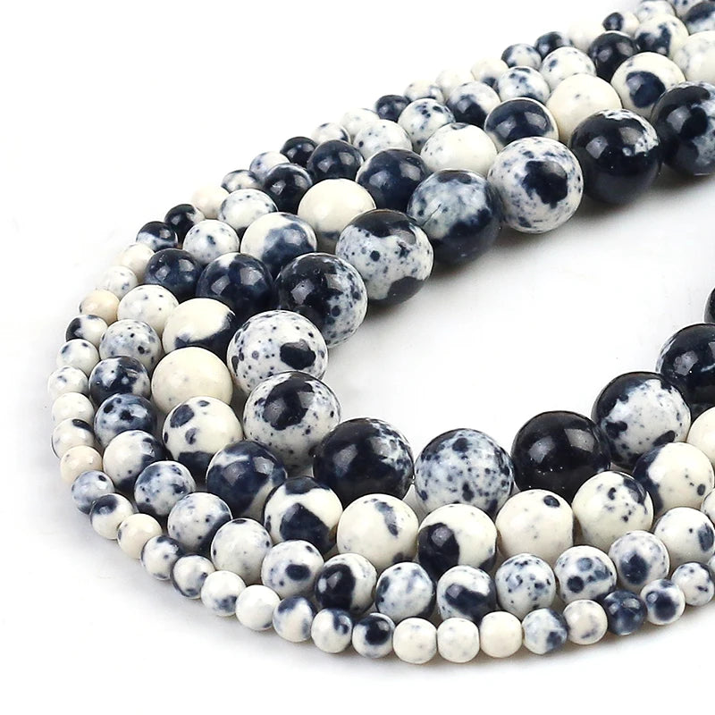 Multiple strands of round gemstone beads in large and small sizes, featuring a mottled pattern of dark navy blue, black, and off-white on a clean white background.