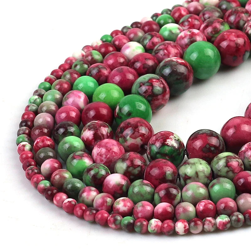 Multicolor round gemstone beads in shades of red, green, pink, and white, arranged in overlapping strands on a white background.