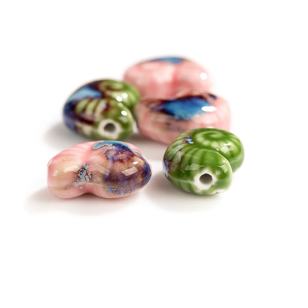 Five glossy ceramic conch beads with marbled patterns in pink, green, blue, and purple on a white background.