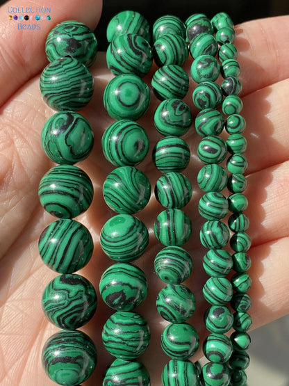 Five strands of green malachite bead bracelets in various sizes, held in a person's hand to show the details and texture of the beads.