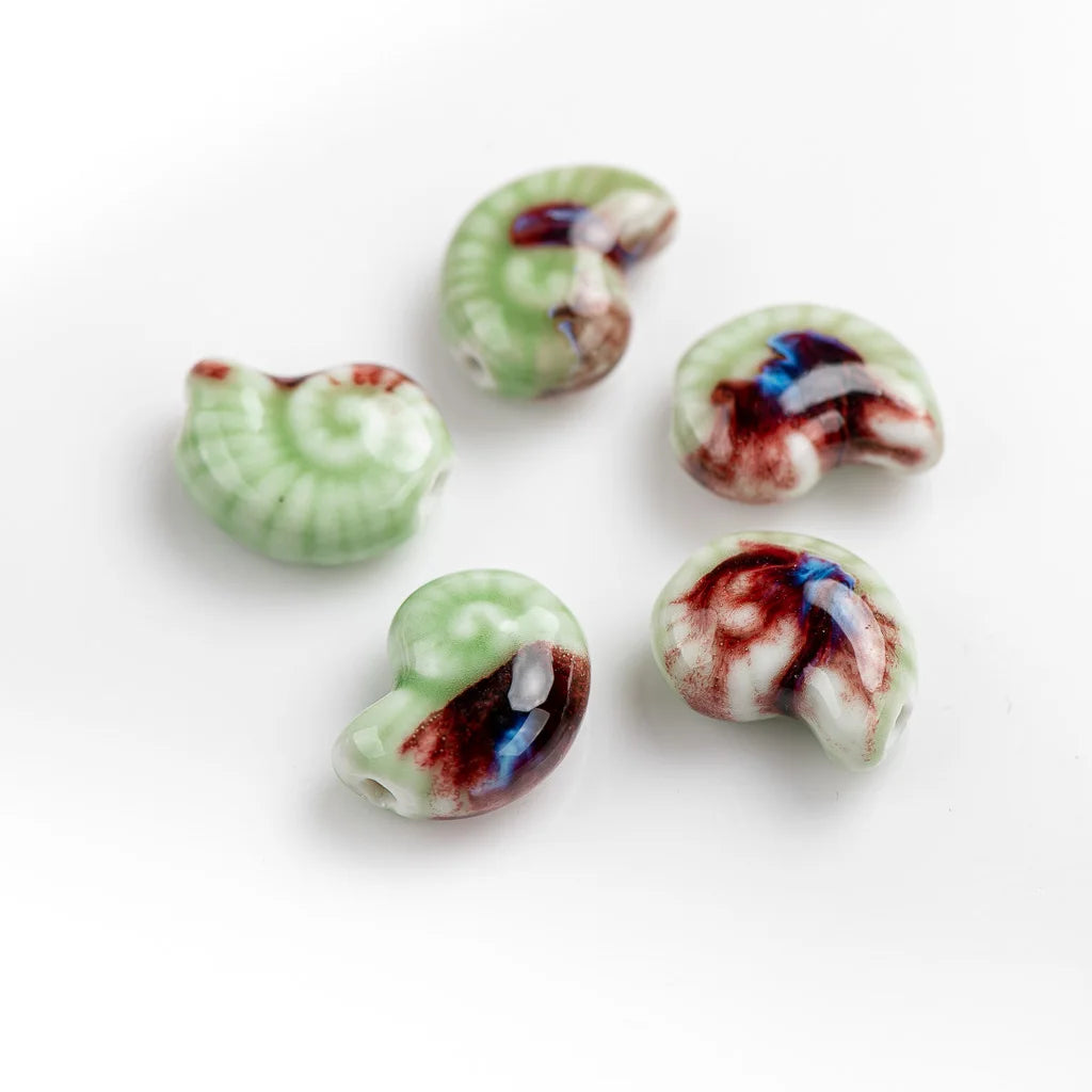 Five small spiral-shaped conch beads with a glossy finish, featuring a light green base with white veining and dark red, blue, and purple marbled accents, arranged on a plain white background.