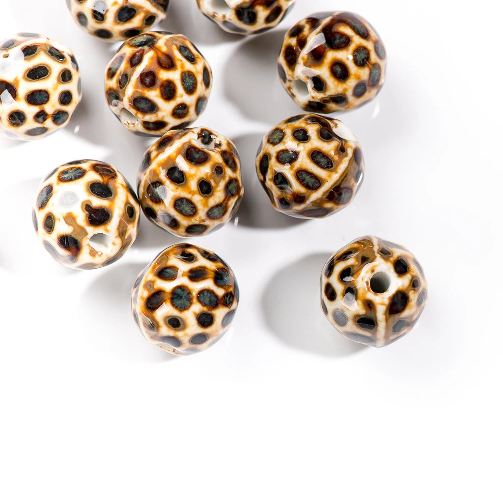 A group of round, glossy glass beads with a brown and black spotted leopard-like pattern on a white background.