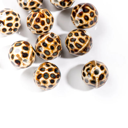 A group of round, glossy glass beads with a brown and black spotted leopard-like pattern on a white background.