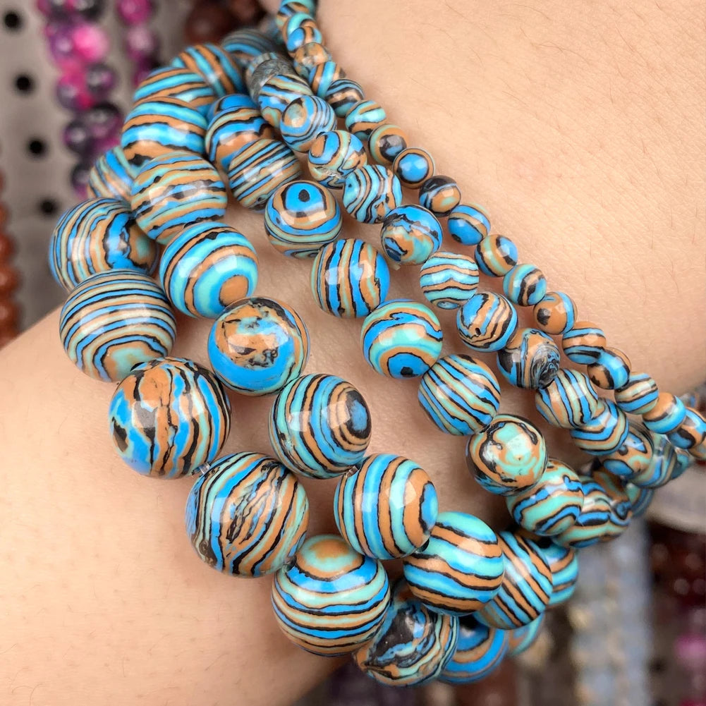 A close-up of a person's wrist wearing multiple strands of turquoise, blue, and brown striped beads.