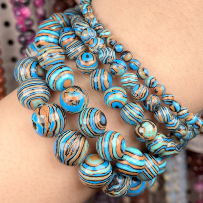 A close-up of a person's wrist wearing multiple strands of turquoise, blue, and brown striped beads.