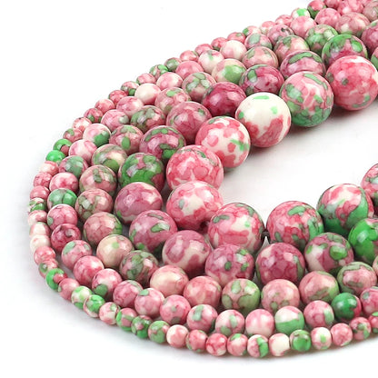 Curled strands of round gemstone beads in pink, white, and green marbled patterns on a white background.