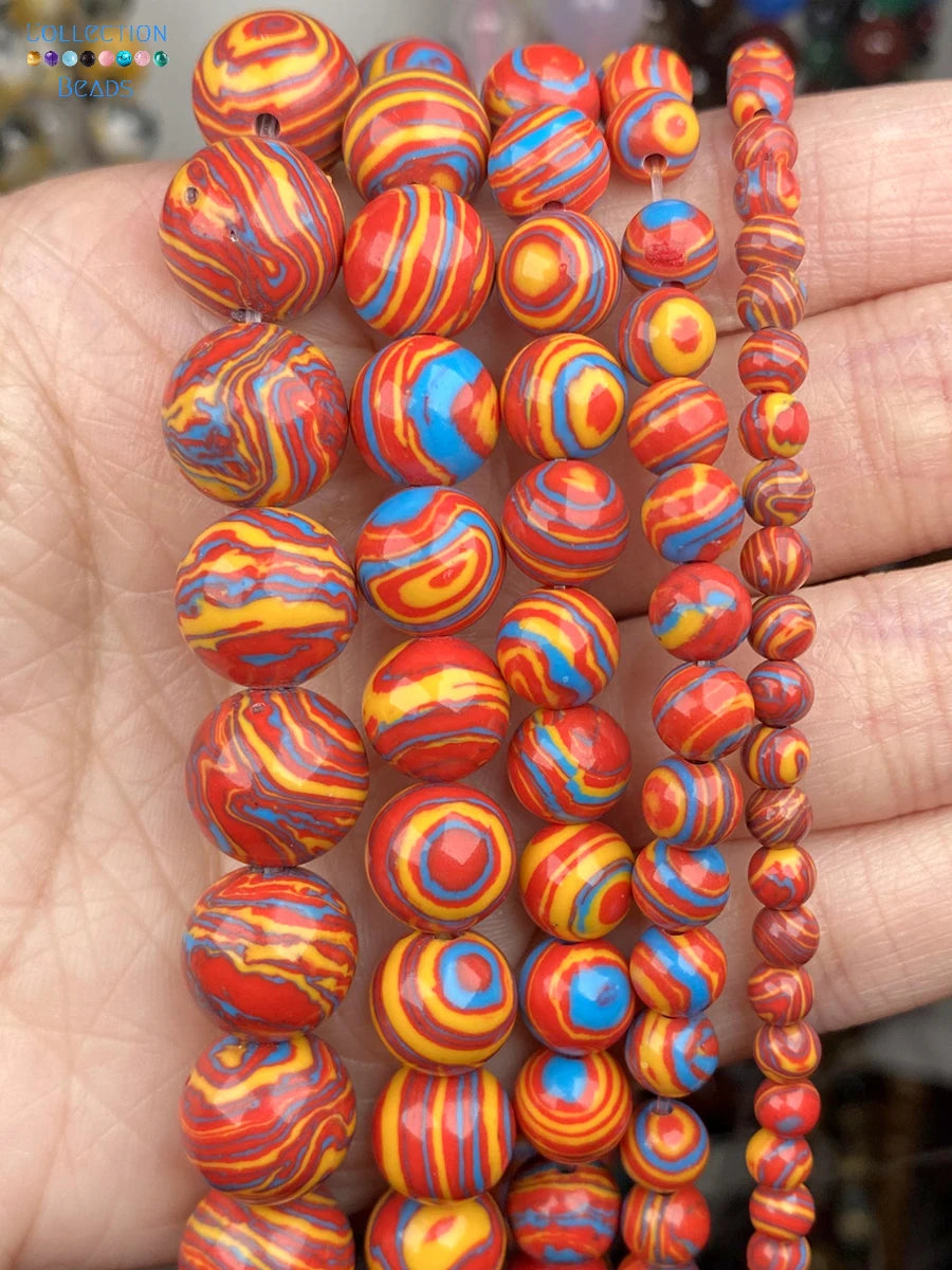 Multiple strands of colorful marbled beads held in a hand. The beads feature swirl patterns in red, orange, yellow, and blue, with some smaller beads on the right strand.