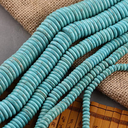 Turquoise round disc beads arranged in strands on a burlap and bamboo background.