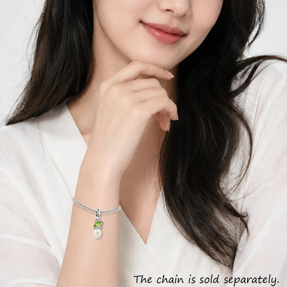 Woman wearing a bracelet with a pendant on a plain background