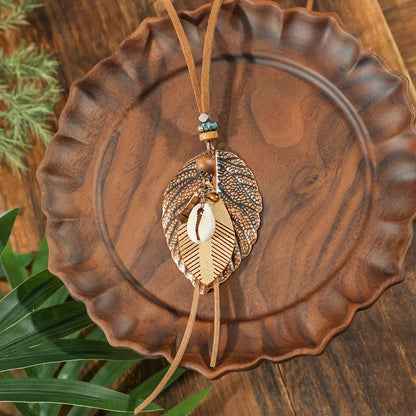 Decorative pendant with leaf design hanging on a wooden plate