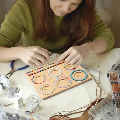 Woman making bracelets with colorful beads on a wooden beadboard.