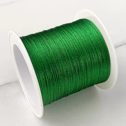 A spool of vibrant green embroidery thread wound tightly on a white plastic core, photographed on a light gray surface.