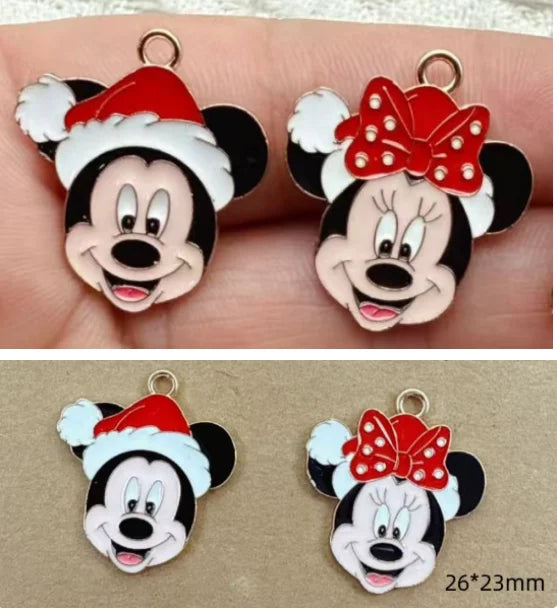 Four Mickey and Minnie Mouse face charms with gold-tone metal edges, shown in two rows. The top row shows the charms resting on a person's fingers, and the bottom row shows them on a tan surface with a size note reading 26*23mm.