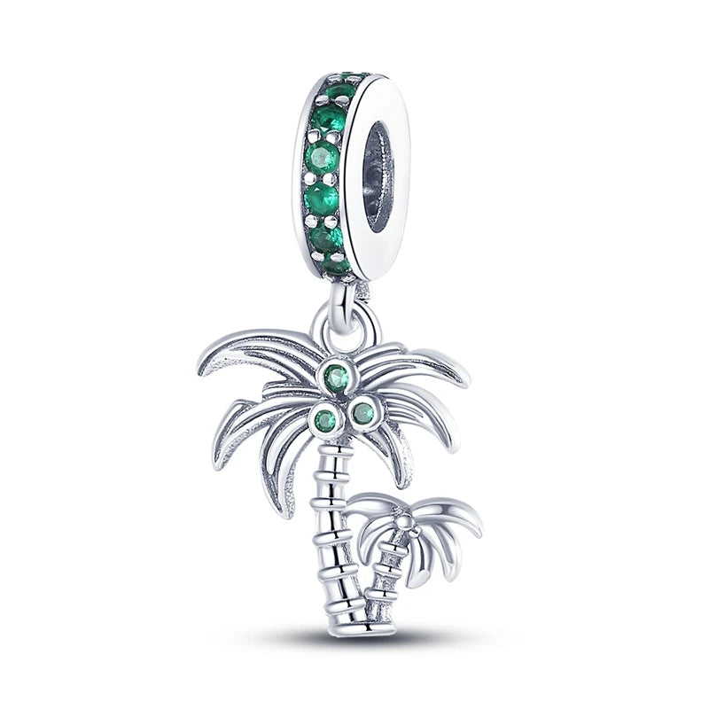 Silver palm tree charm with green gemstones on a white background