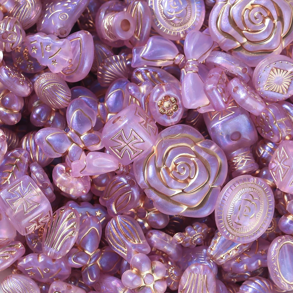 Close-up of pink and gold decorative beads with floral and circular designs.