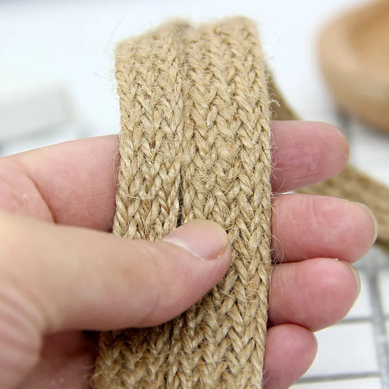Close-up of a hand holding a piece of woven jute fiber.