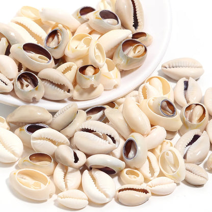 A pile of glossy cowrie shells with cream, beige, and white tones, with a white plate holding some of them on a clean white background.
