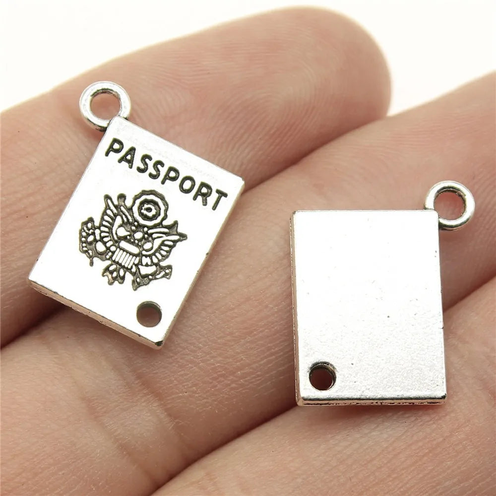 Silver 'Passport' charm with eagle emblem held between fingers