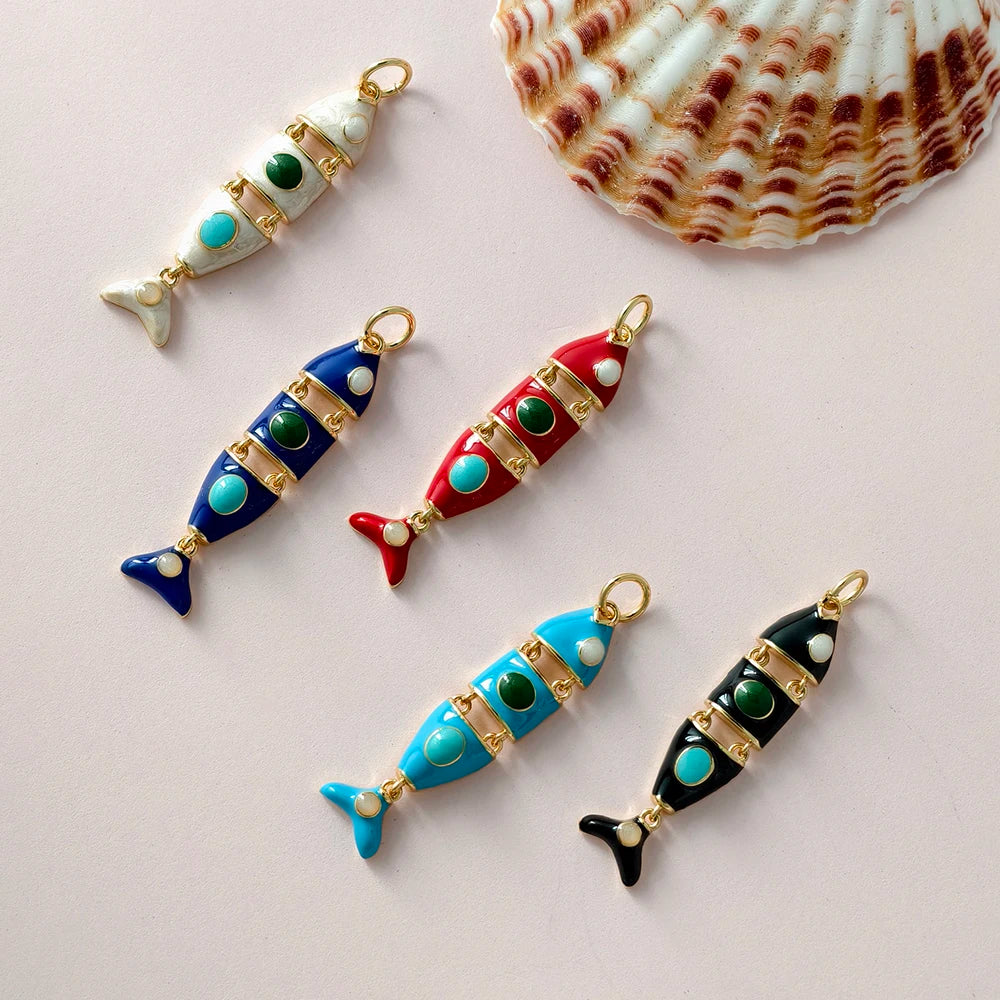 Colorful fish-shaped charms with gold accents on a light pink background