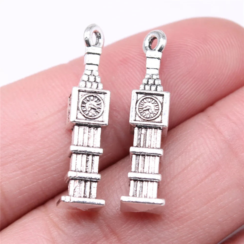 Two silver Big Ben clock tower charms held between fingers on a white background