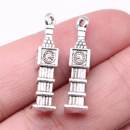 Two silver Big Ben clock tower charms held between fingers on a white background