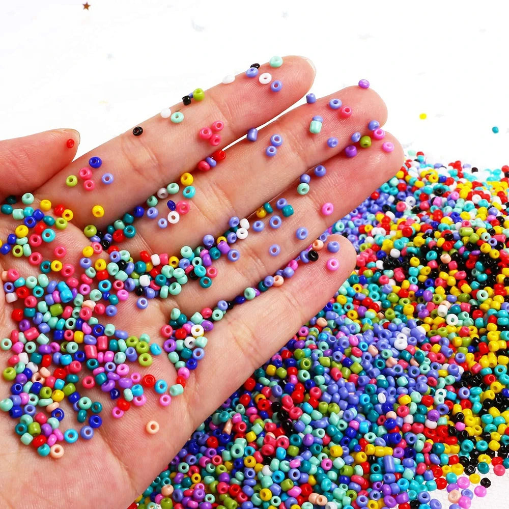 Colorful small beads scattered on a hand and surrounding area with a white background