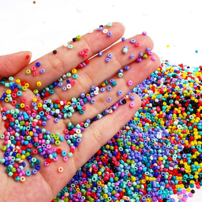 Colorful small beads scattered on a hand and surrounding area with a white background