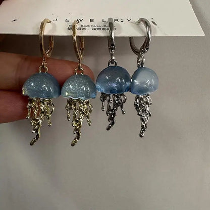 Jellyfish-shaped earrings with gold and silver hooks on a jewelry card.
