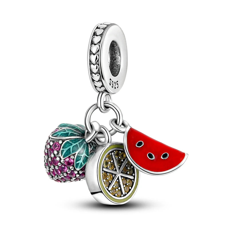 A sterling silver dangle charm featuring three colorful enamel and crystal details: a strawberry with green and pink enamel, a red watermelon slice, and a lemon wheel with gold-toned crystal accents, all attached to a heart-patterned silver bead.